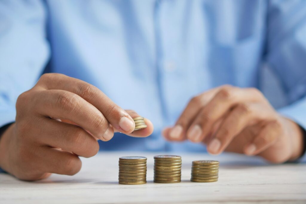 يد ترتّب أكوام العملات النقدية ترمز للتخطيط المالي