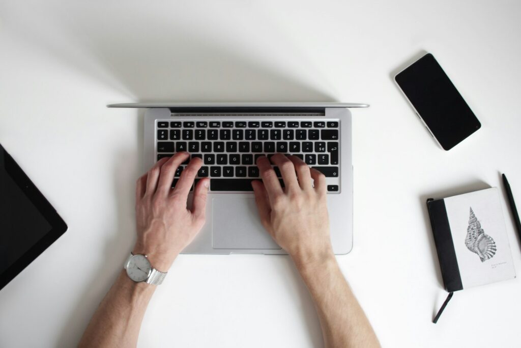يدان تكتبان على حاسوب محمول ترمز للعصر الرقمي